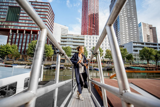 Young woman traveling at the modern harbor with skyscrapers on the background in Rotterdam city
