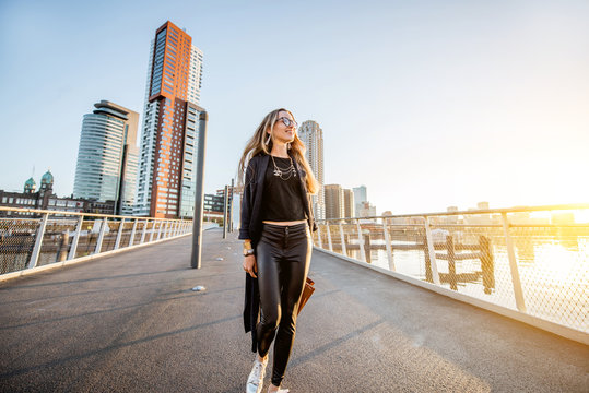 Lifestyle portrait of a young stylish businesswoman walking the bridge during the morning in Rotterdam
