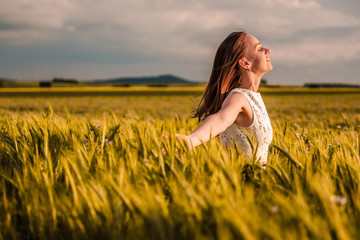 Beautiful woman in white dress on golden yellow wheat field