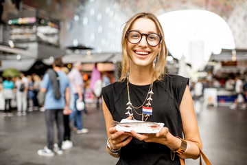 Young woman eating herring with onions traditional dutch snack in Rotterdam market