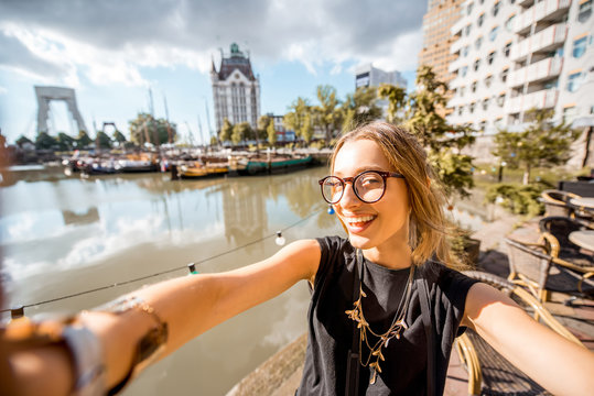 Young woman tourist making selfie photo standing at the old harbor in Rotterdam city