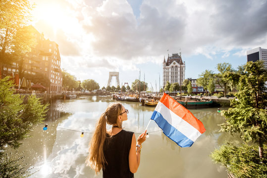 Young woman tourist standing back with dutch flag at the old harbor in Rotterdam city
