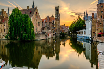 Naklejka premium Miasto Brugia (Brugge) z kanałem wodnym o zachodzie słońca