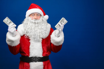 Fototapeta na wymiar Santa Claus holding money on color background