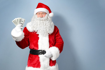 Fototapeta na wymiar Santa Claus holding money on light background