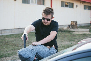 Obraz premium Arrest of thieves, criminals, hands bound with police cuffs, a gun directed at the head, a thief disabled, leaning on the hood of a police car