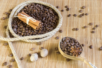 Coffee beans in a ring of hemp, star anise on the background bamboo Mat. Next to the wooden spoon with allspice.