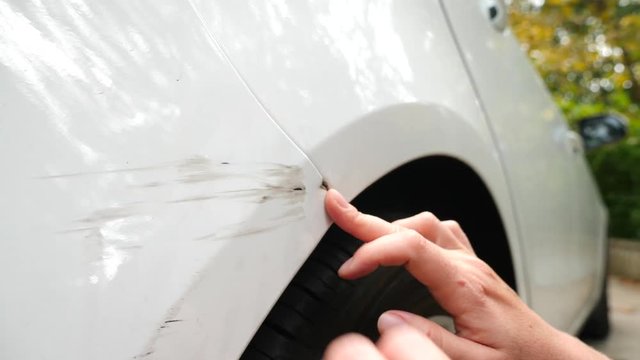 looking at a damaged vehicle. Woman blonde inspects car damage after an accident. 4k, slow-motion
