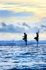 Traditional fishermen on sticks at the sunset in Sri Lanka. Seascape image in blue and yellow colors.