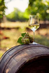Papier Peint photo Vin A glass of white wine with grapes on a barrel