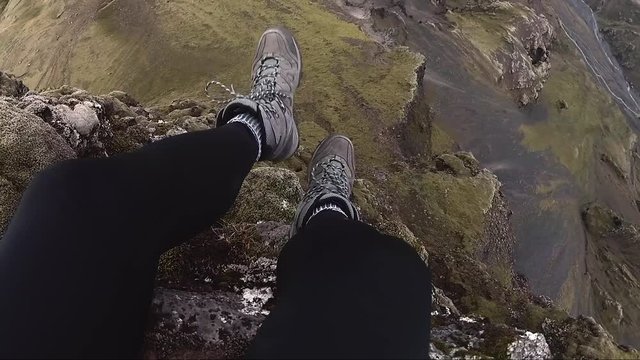 A hiker dangles his legs over the edge of a cliff