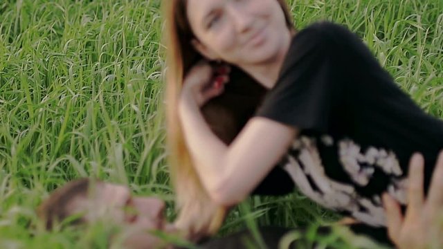Girl lies on the grass and throws back her hair slow motion