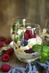 Delisious traditional english dessert eton mess with fresh berries in a glass .