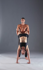 Obraz premium Young couple practicing acro yoga on mat in studio together. Acroyoga. Couple yoga. Partner yoga.