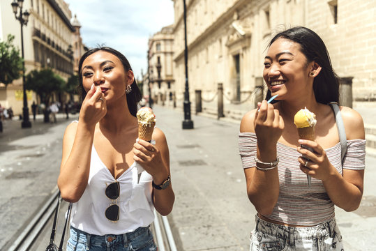 Two Chinese girls eating ice cream walking