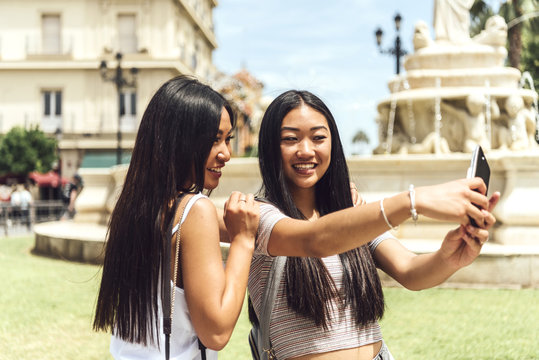 Two Chinese girl taking selfie at fountain