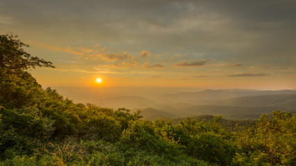 Idyllic sunset over the forest of the Shenandoah valley with yellows and oranges cast upon the sky and trees