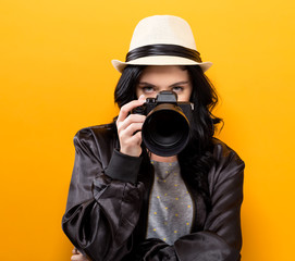  Young woman holding a camera on a yellow background