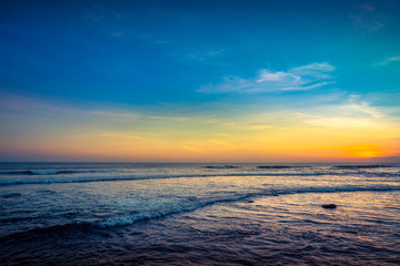 Blue Waves near sea Resort. Isolated Sea Sunset. Surfing Beach with Surfers on the Horizon. Landscape. Sunset Background Ocean. Tropical Sunlight and Summer Sunset View. Colorful Background Sunset. 