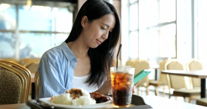 Woman looking on cellphone with her lunch in restaurant