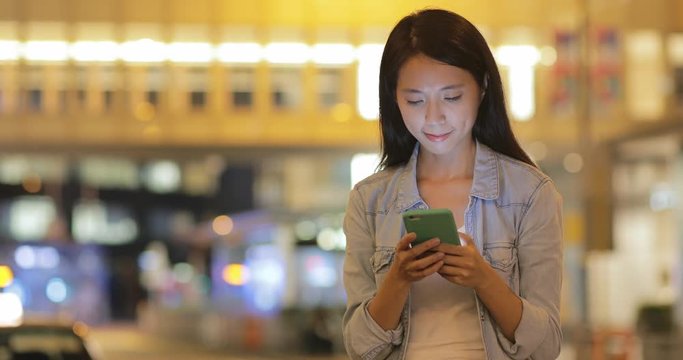 Woman touching mobile phone at night