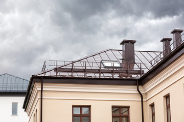 Fototapeta na wymiar house with brown metal wet roof, chimneys and skylights during rain
