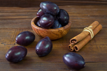 Plums in the bowl and plums sprinkled on the table