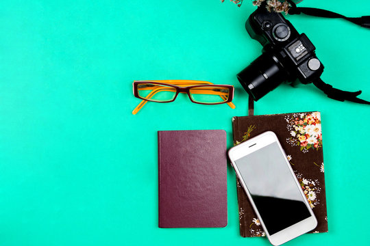 Flat lay travel concept with camera, mobile phone on green background