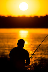 Fisherman with a fishing rod at sunset