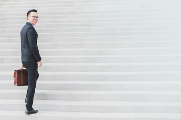 Asian Smart Businessman walking up the stairs.Concept of success business step.
