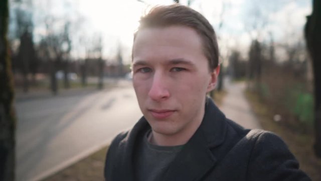 young man walking on street in town in spring and filming himself