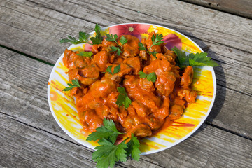 Chicken gizzard stew in plate on rustic wooden table