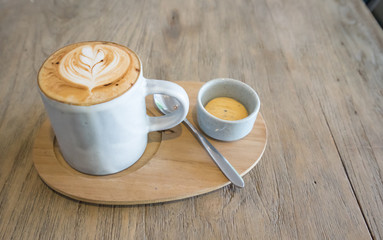 hot latte coffee with cracker on vintage wood table in cafe