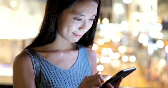 Woman looking at smart phone over the traffic background