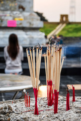 Incense sticks in the incense burner at the temple with Blur young woman Traveler praying in background. Incense sticks at Buddhism temple in Asia Travel concept.