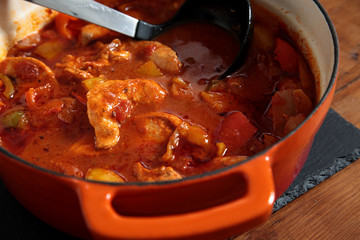 Chicken paprika casserole in a ceramic dish with a ladle