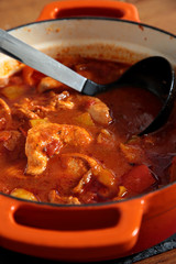 Chicken paprika casserole in a ceramic dish with a ladle