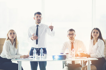 The business people sit at the table and discuss near the projector