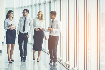 The business people walk in the office hall on the sunny background