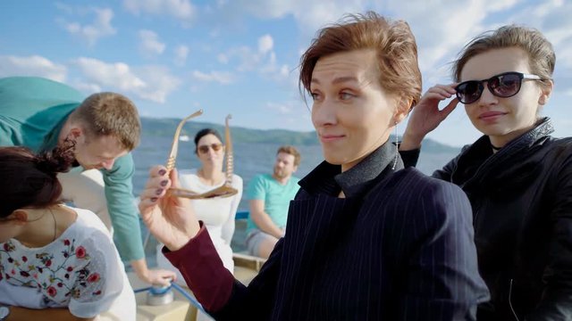 A company of young friends are riding the sea on a boat, friends went on a tourist trip on a watercraft on a warm summer day, small waves rumble the boat