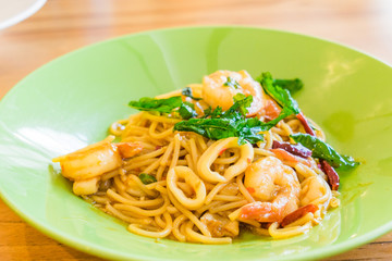 Spicy Spaghetti Seafood in a green plate on wooden background