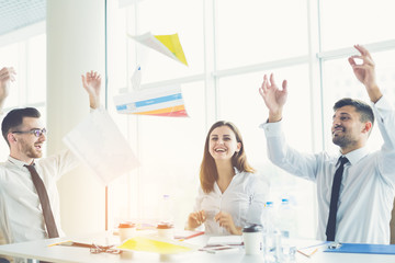 The business people throw papers at the table on the sun background