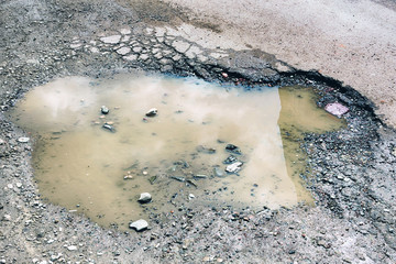 Background texture road pothole pothole with puddles on asphalt road close-up hdr