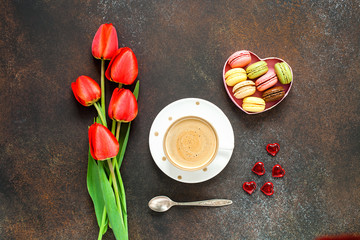Red tulips, macarons and coffee cup on dark table. Top view with copy space