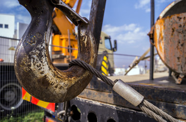 a crane hook hooked to a steel wire with machinery blurred in the background