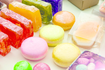 photo handmade soap in the form of sweets, heart, canteen, fruit, in boxes on the table close-up as background under the inscription