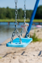 Brigth blue swing in watter park hanged on metal chain