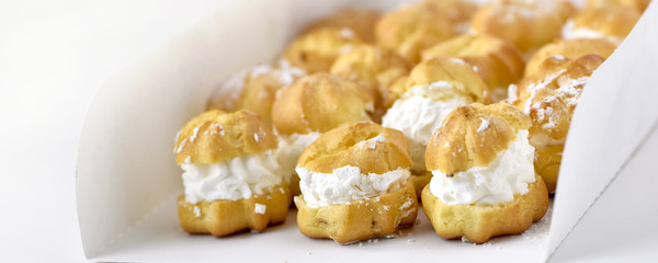 Profiteroles or cream puff cakes in white paper box
