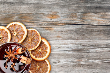 mulled wine and orange slices on rustic wooden background