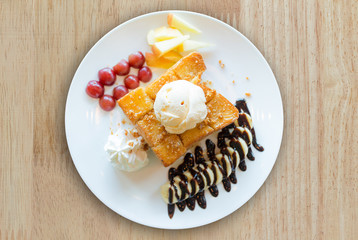 Honey toast with vanilla ice cream, whipped cream and chocolate syrup. Served with banana, grape and apple(selective focus)